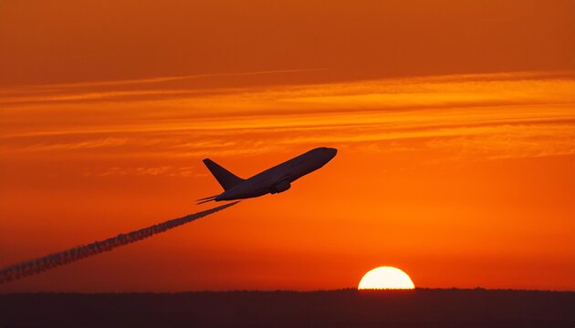 A twin-engine jet climbing at sunset, trailing a contrail